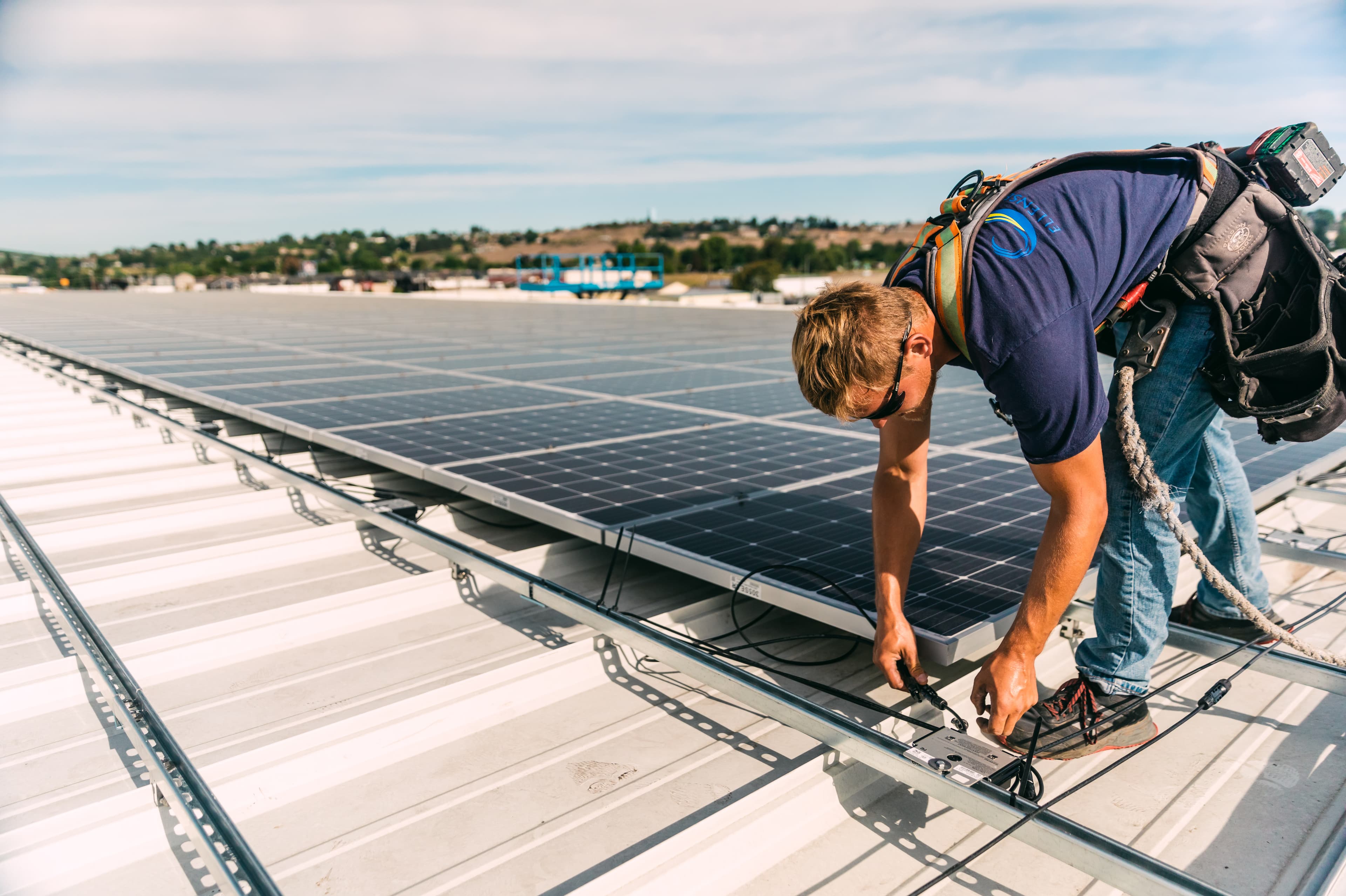 A man installs a solar panel on roof of building