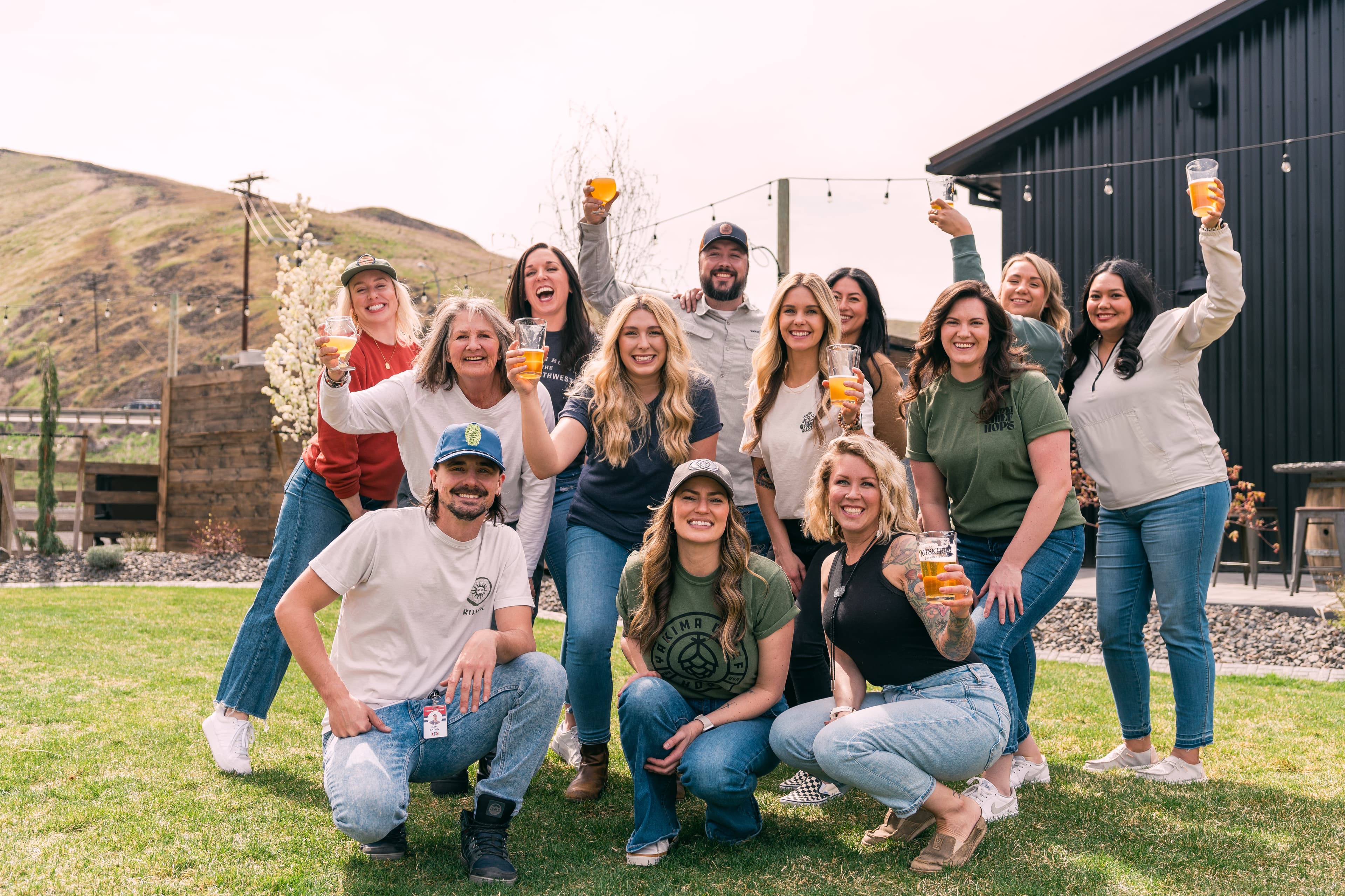 Employees huddle together in a group, smiling, and raising glasses in celebration.