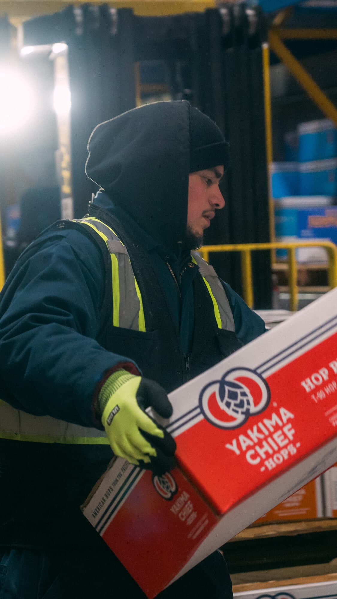 Employee picks up a box of YCH Hop Pellets