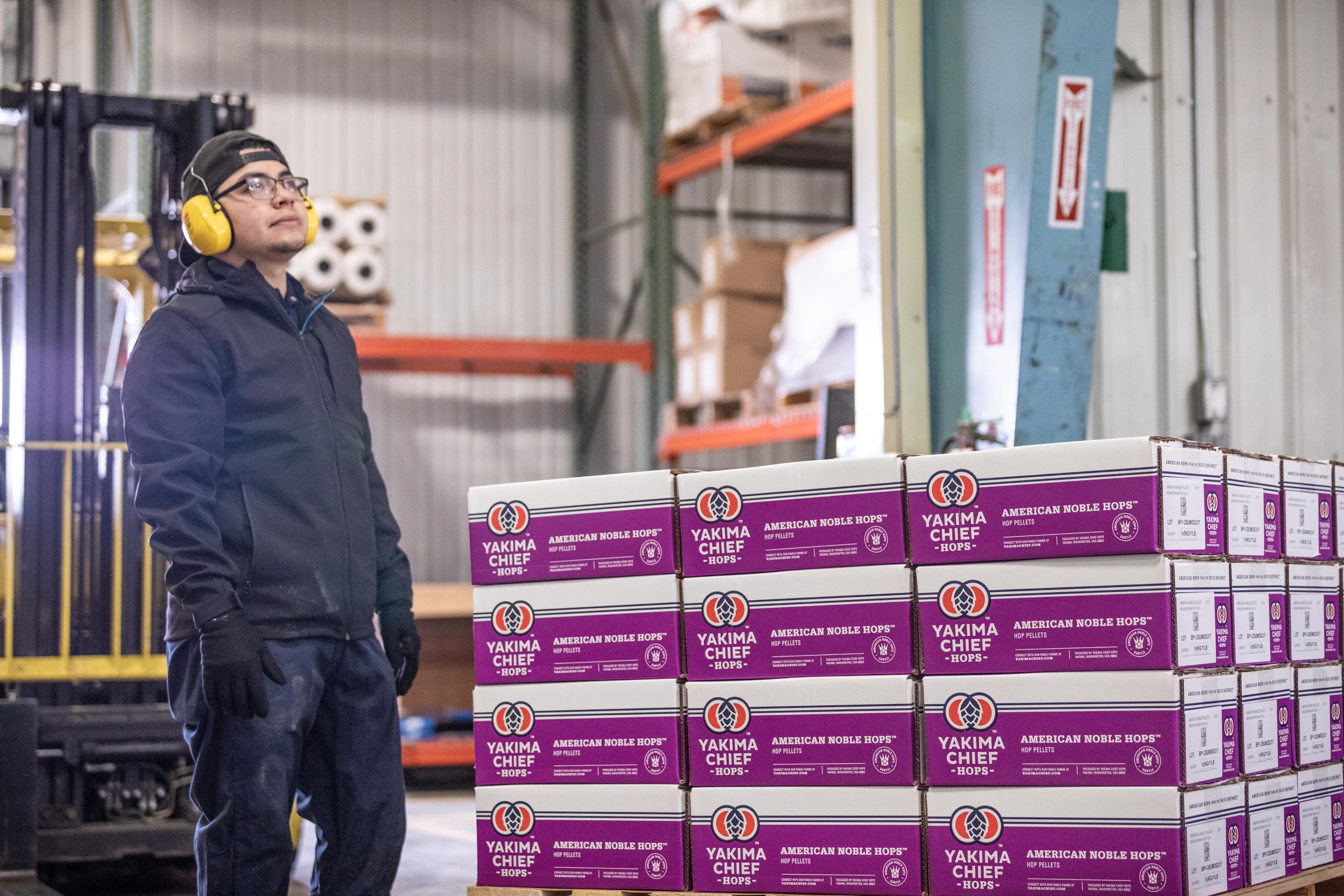 Pallet of purple American Noble boxes with employee standing to the left