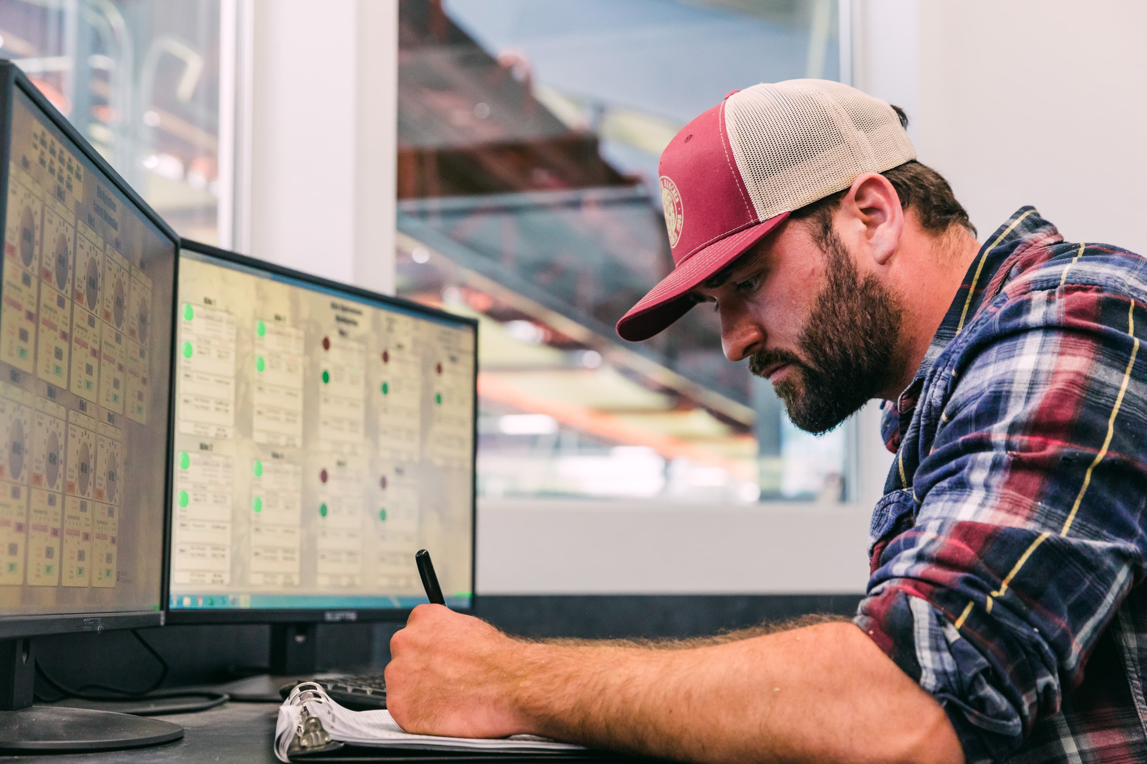 Grower writing on clipboard in front of computer screen with kiln data