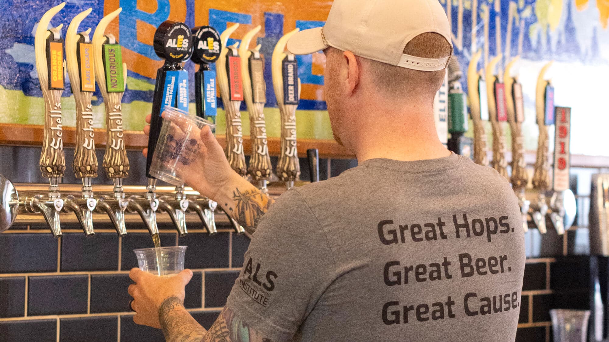Beertender wearing Ales for ALS branded shirt pours beer from tap